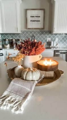 a white kitchen counter top with a candle and some pumpkins on the plate next to it