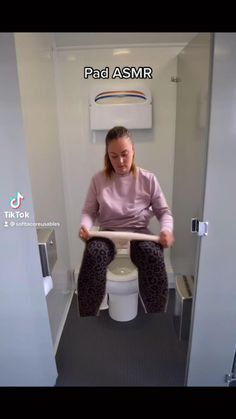 a woman sitting on top of a toilet with her legs crossed and holding onto the seat