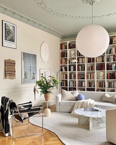 a living room filled with lots of furniture next to a book shelf covered in books