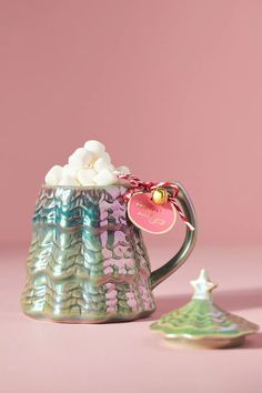 a mug with marshmallows in it next to a cookie