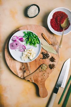 a wooden cutting board topped with different types of food next to a knife and spoon