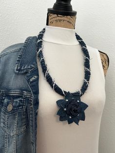 a woman wearing a denim jacket with a flower necklace on top of her neck,