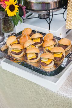 mini cheeseburgers are arranged on a tray with toothpicks