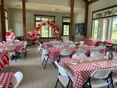 a room filled with lots of tables covered in red and white checkered cloths