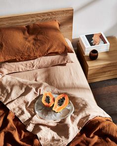 a plate with two pieces of fruit on it sitting on a bed next to an open book