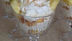 two desserts with bananas and whipped cream in glass cups