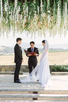 a bride and groom are standing under an altar