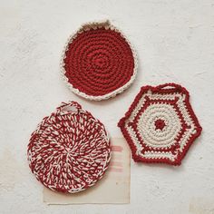 three crocheted baskets sitting next to each other on a white surface with a piece of paper in front of them