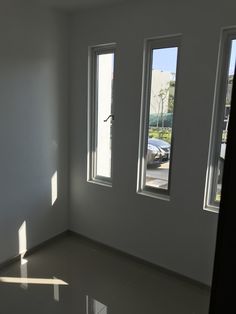 an empty room with three windows and one car parked in the lot next to it