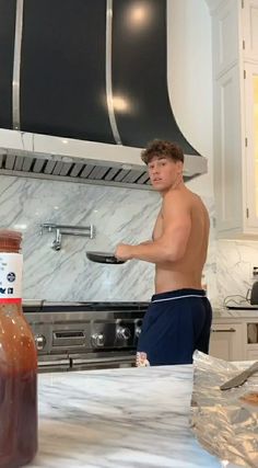 a shirtless man standing in front of a bottle of ketchup on top of a counter