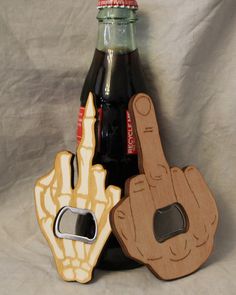 two wooden hand shaped magnets next to a bottle of soda