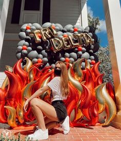 a woman sitting on the ground in front of some balloons