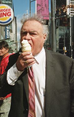 a man in a suit eating an ice cream cone on the street with a burger king sign behind him