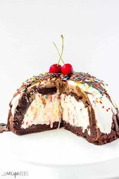 a chocolate cake with white frosting and sprinkles on top, topped with two cherries