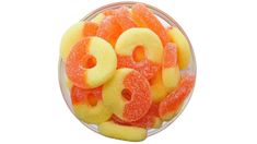 a bowl filled with orange and yellow gummy donuts on top of a white surface