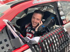 a man sitting in the driver's seat of a race car talking on his cell phone