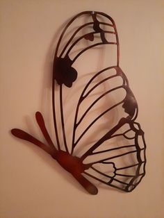 a metal butterfly sculpture mounted to the side of a wall