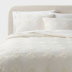 a bed with white linens and pillows on top of the headboard is shown