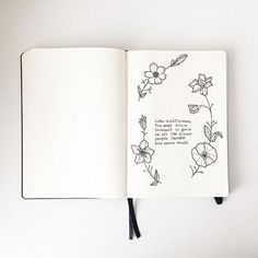 an open notebook with a drawing of flowers on the page and a handwritten quote