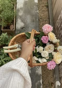 a person holding a basket with flowers in it