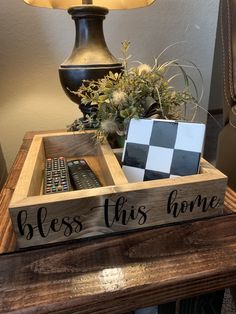 a wooden box with a remote control on it and a lamp next to it that says, bess this home