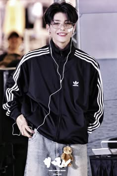 a young man with headphones standing in front of a wall and smiling at the camera