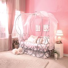 a pink bedroom with a canopy bed and two cats laying on the floor next to it