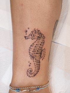 a small seahorse tattoo on the side of a woman's leg and ankle