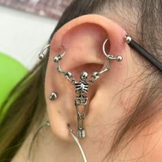 a person with ear piercings on their ears and behind the ear is a skeleton