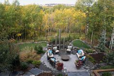 an aerial view of a patio with chairs and fire pit surrounded by trees in the background