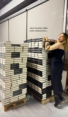 a woman standing next to stacks of books