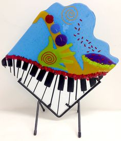 an artistically designed piano sitting on top of a metal stand with music notes painted on it