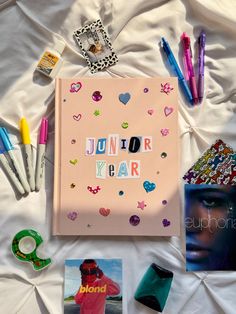 a pink book with writing on it next to pens and other items that include photos