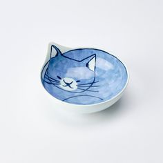 a blue and white bowl with a cat design on the front, sitting on a white surface