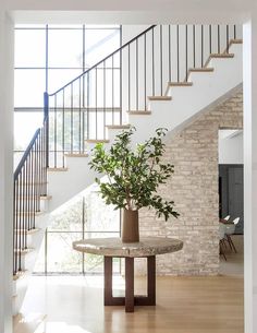 a plant in a vase sitting on top of a table next to a stair case