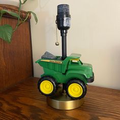 a green toy truck sitting on top of a wooden table next to a black phone