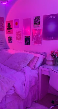 a bedroom with pink lighting and pictures on the wall above the bed, along with a desk