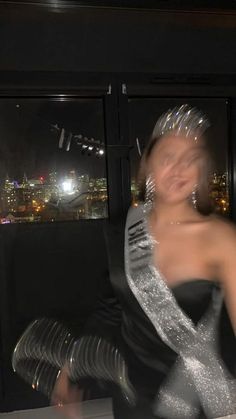 a woman wearing a silver and black dress dancing in front of a window at night