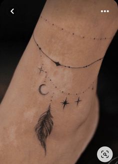 a foot with a tattoo on it that has stars and a feather hanging from the ankle