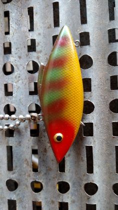 a fishing lure hanging from a chain on a piece of metal