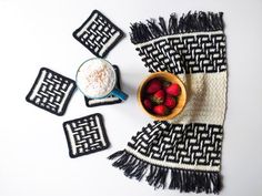 strawberries in a bowl and two coasters on a table with a black and white blanket