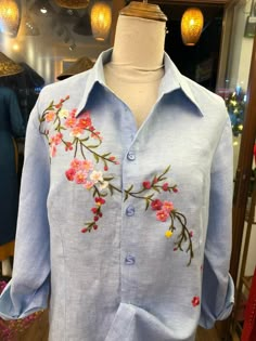 a blue shirt with pink and yellow flowers is on display in a storefront window