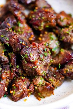 a white plate topped with meat covered in sauce and garnished with parsley