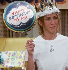 a woman wearing a birthday hat holding a balloon with the words happy birthday to me on it