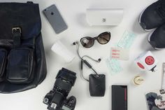 the contents of a camera bag laid out on a table with sunglasses, cell phone and other items