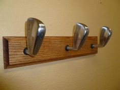 three metal golf club heads mounted to a wooden holder on a wall in a room