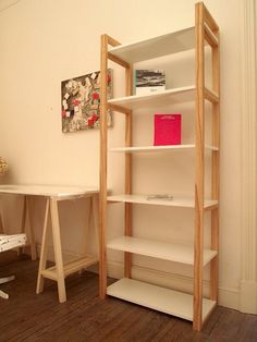 a book shelf sitting in the corner of a room next to a desk and chair