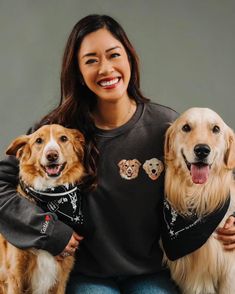 a woman sitting with two dogs wearing bandanas