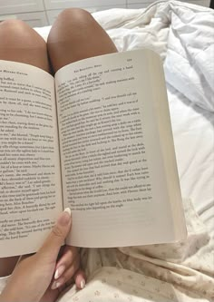 a person laying in bed with their legs crossed and reading a book on top of the bed