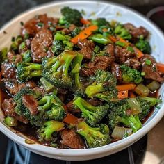 a white bowl filled with beef and broccoli